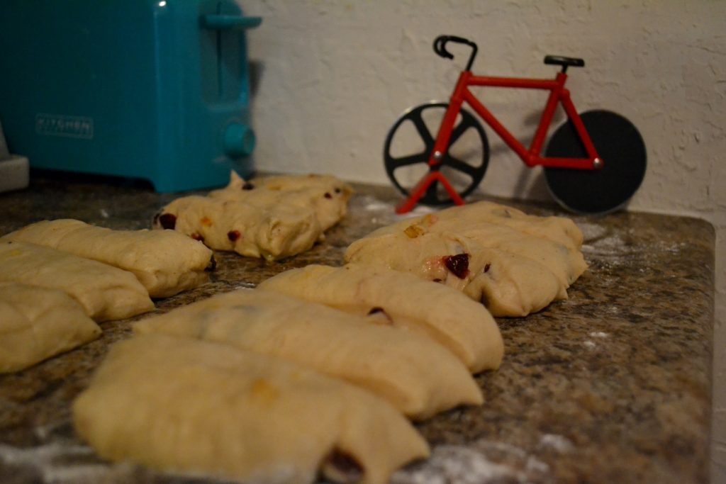 Cranberry Orange Hot Cross Buns dough after being cut with bicycle pizza cutter in background