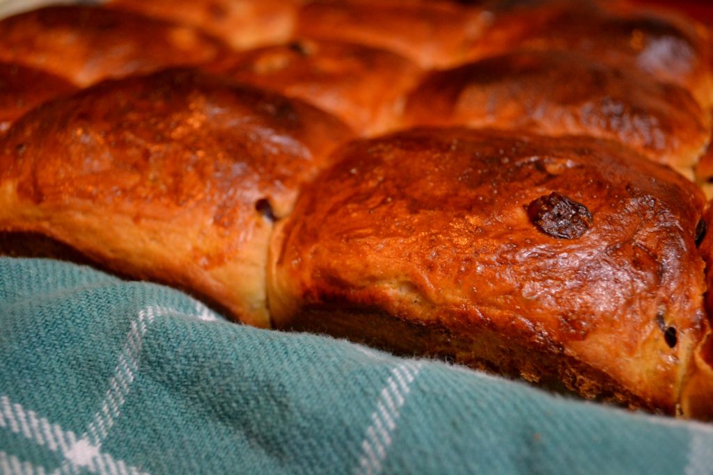 Cranberry Orange Hot Cross Buns from side on green towel without icing