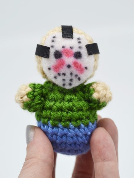 up close of hand holding a small amigurumi crochet dolls of jason from friday the 13th