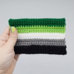 hand holding a crochet aromantic pride flag