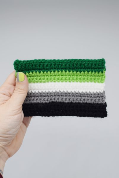 hand holding a crochet aromantic pride flag