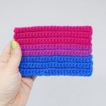 Hand holding a crochet bisexual pride flag