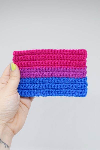 Hand holding a crochet bisexual pride flag