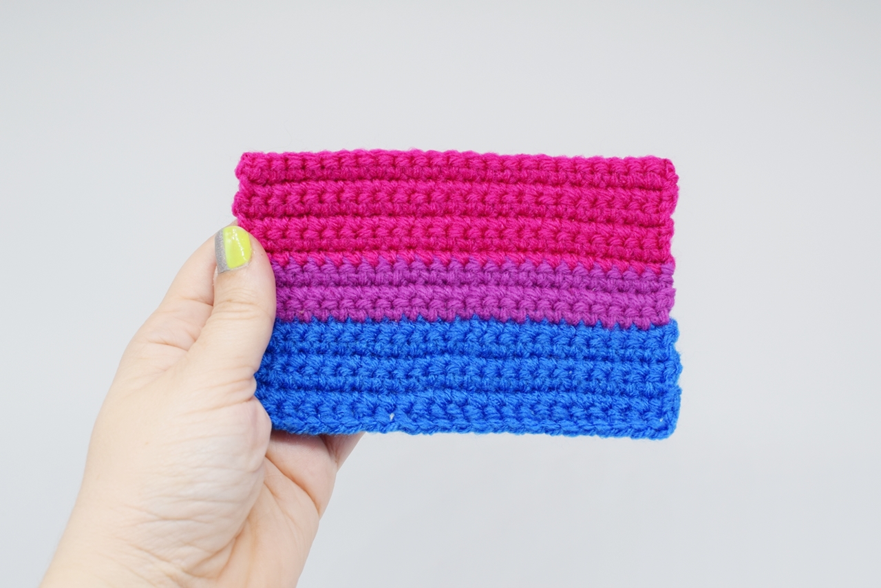 Hand holding a crochet bisexual pride flag