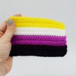 Hand holding a Crochet Non-binary Pride flag on a white background