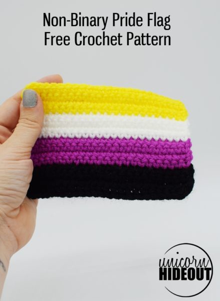 Hand holding a Crochet Non-binary Pride flag on a white background, words on image say "Non-Binary Pride Flag Free Crochet Pattern Unicorn Hideout"