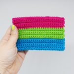 Hand holding Crochet polysexual pride flag on a white background