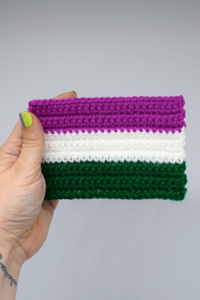 Hand holding Mini Crochet Genderqueer Pride Flag on white background