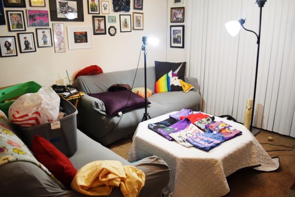 A living room with shirts laid out on a coffee table and two lights shining on them