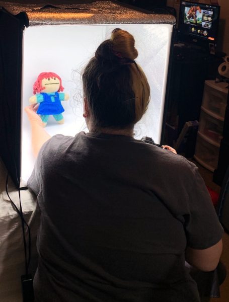 Carly holds a crochet doll in a lightbox 