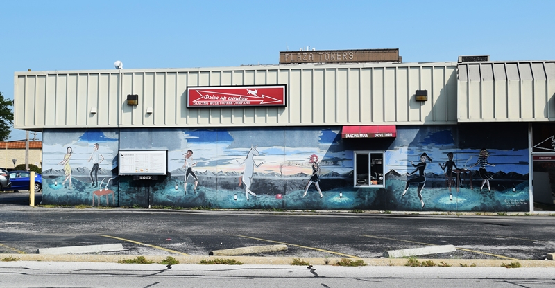 Mural on the side of a building with people dancing and a mule