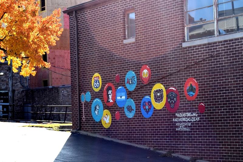 Mural with multi-colored bubbles with different things inside them on the side of a brick building