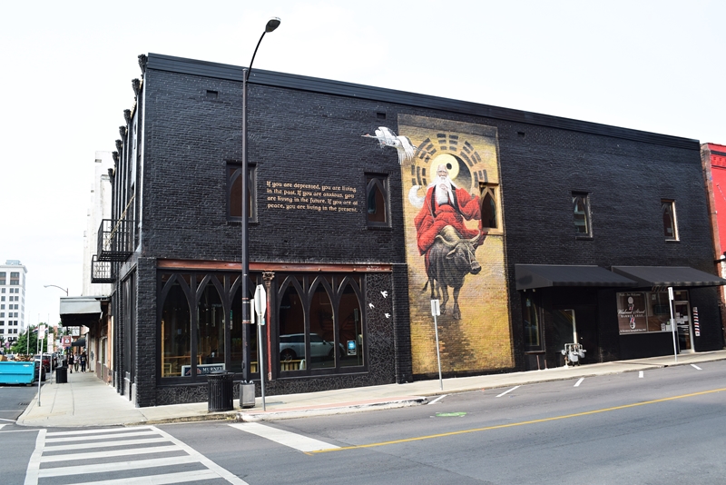 Large two story mural of Lao Tzu on a black brick building