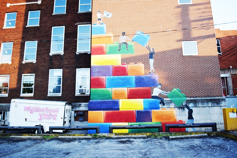 Three story mural of giant lego bricks on the side of a brick building