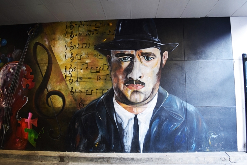 Mural of a portrait of Tom Hanks with sheet music in the background