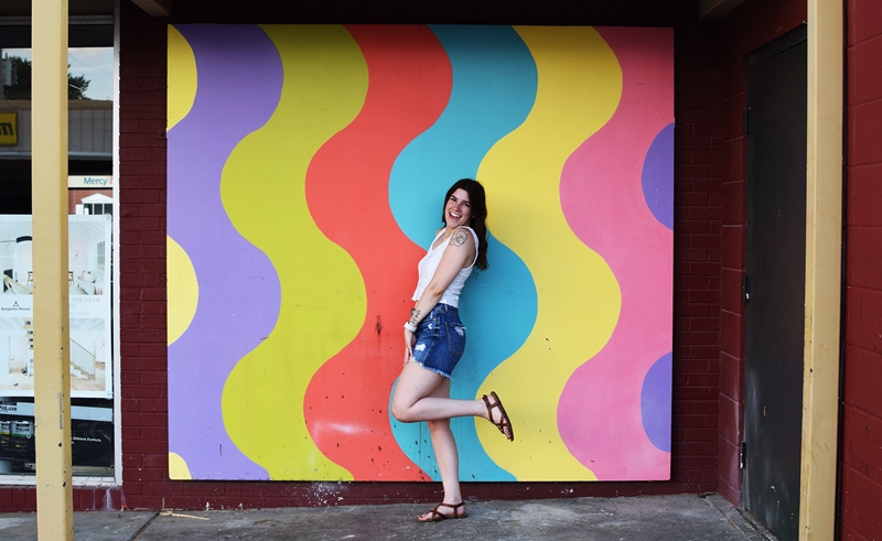 Tiffany stands in front of a wavy rainbow mural 